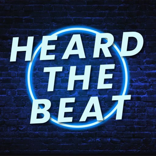 Heard The Beat logo with bold white text inside a glowing blue neon circle on a dark brick wall background