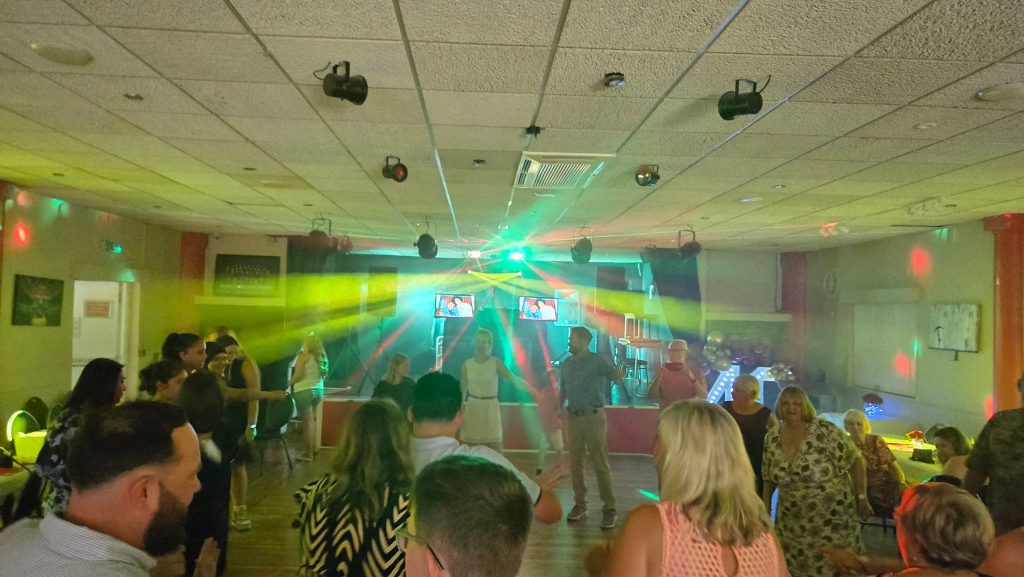 Guests dancing at RNA Gosport with bright green and yellow DJ lights creating a lively party atmosphere.