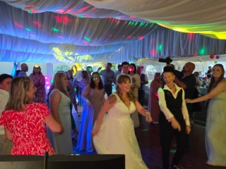 Bride and guests enjoying the dance floor under fun disco lights at a wedding reception.