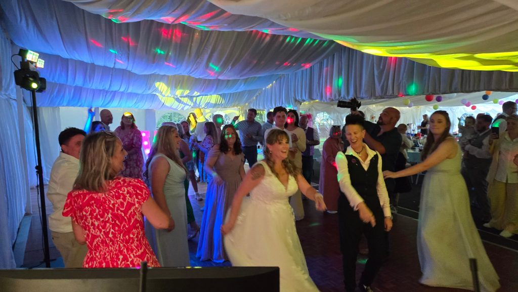 Bride and guests enjoying the dance floor under fun disco lights at a wedding reception.