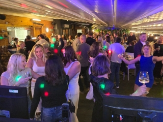 Large crowd celebrating at a party in a stylish bar venue with disco lighting and dancing.