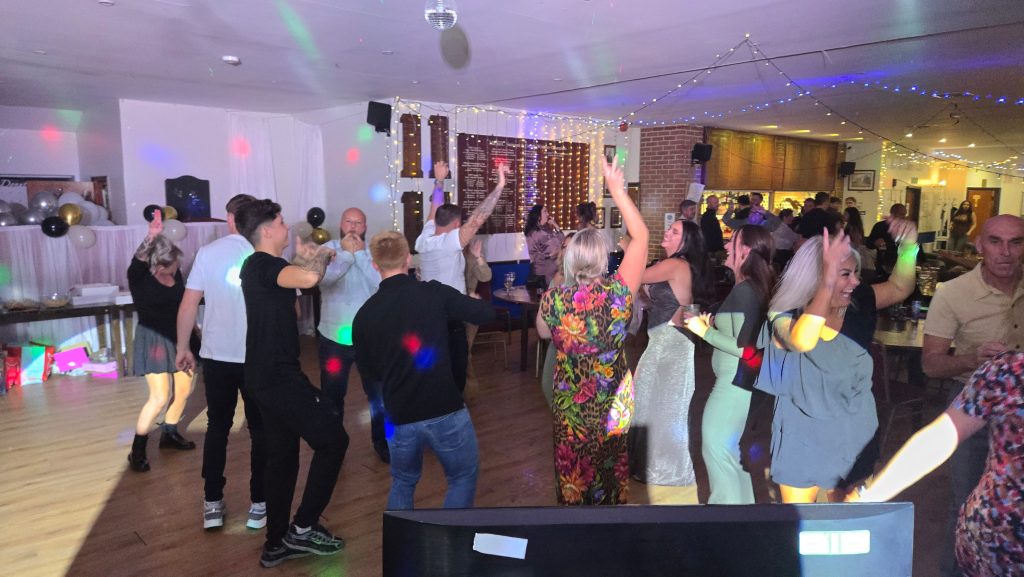 A lively group of guests dancing under colourful disco lights at a 40th birthday party with Heard The Beat DJ in Portsmouth.