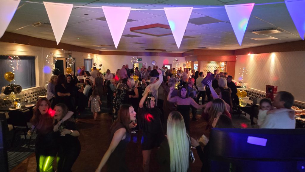 A lively dance floor at Broad Oak Social Club during Jo’s 60th birthday party with guests dancing and party lighting.