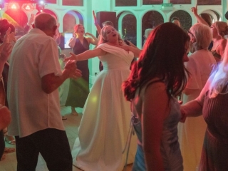 Bride dancing with guests on a packed dance floor during a wedding evening reception