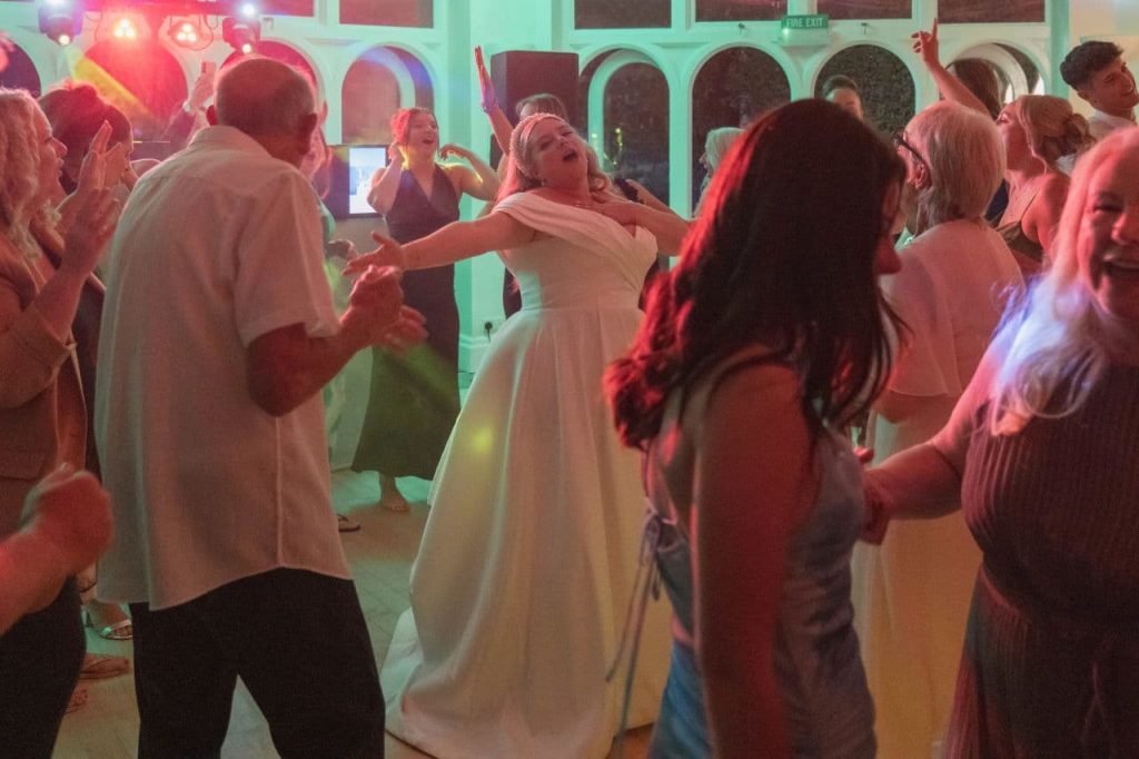 Bride dancing with guests on a packed dance floor during a wedding evening reception