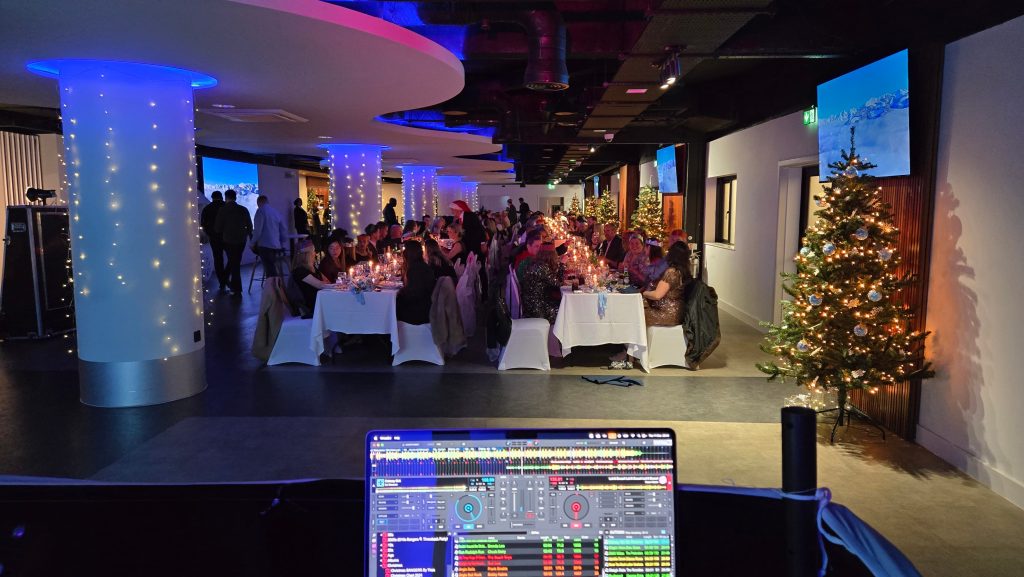 DJ view of corporate Christmas party at the Victory Suite Fratton Park with guests dining and festive décor