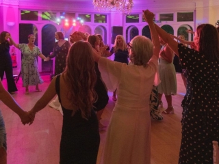 Wedding guests dancing together on a packed dance floor during the evening reception