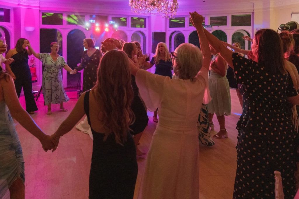Wedding guests dancing together on a packed dance floor during the evening reception