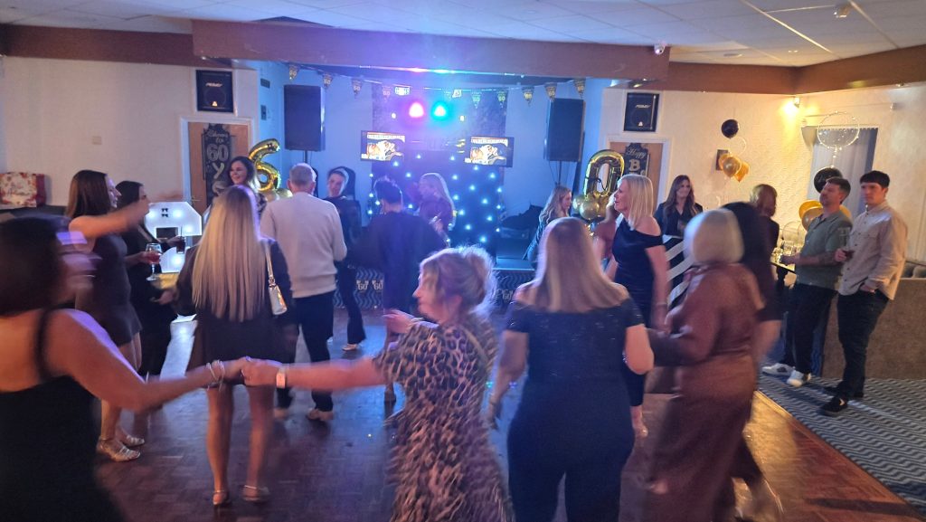 Evening party at Broad Oak Social Club with guests dancing and DJ booth in view