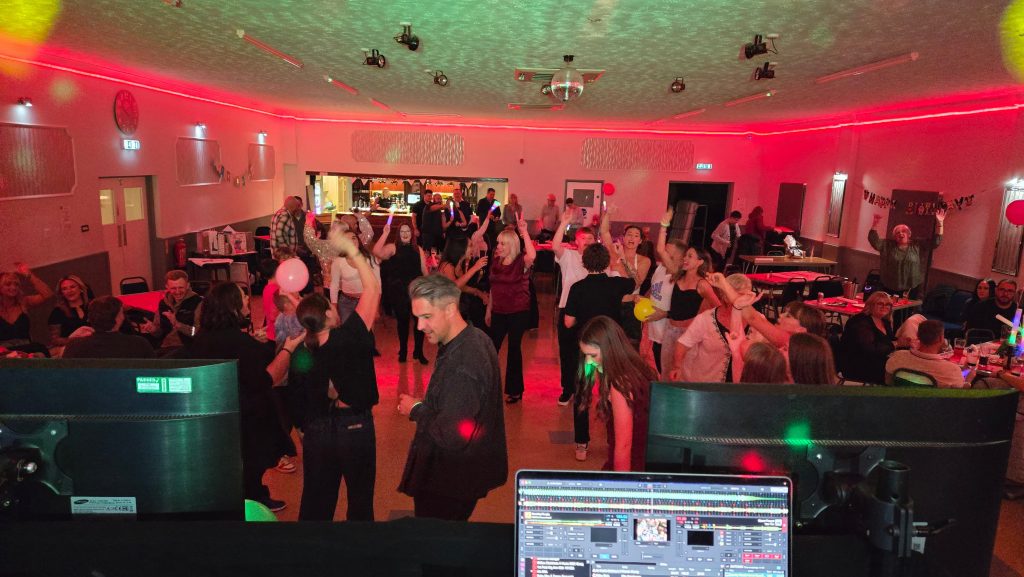 Evening party at Lee-On-Solent Community Association with guests dancing and DJ booth in view