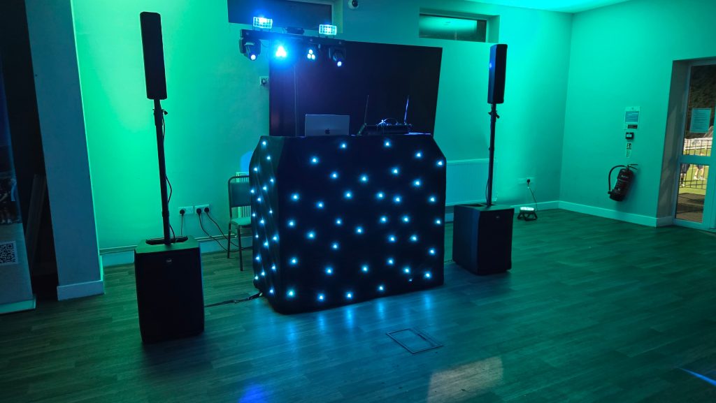 Professional school event DJ setup with LED starcloth booth, speakers and colourful lighting ready for a school disco