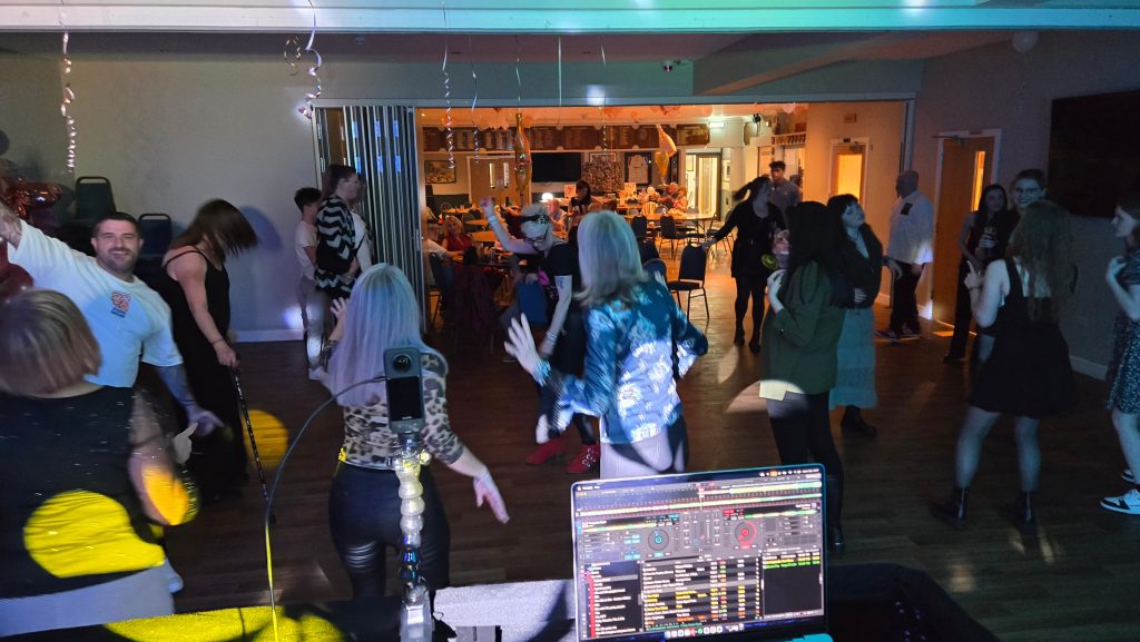 Crowd enjoying a 21st birthday party at Havant Rugby Club with DJ booth and lighting creating a lively atmosphere