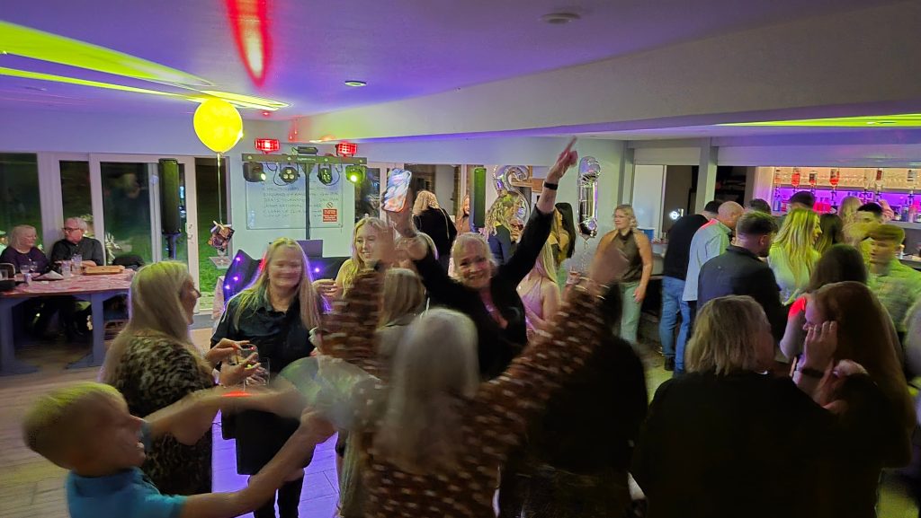 Guests enjoying a busy dancefloor at Pagham Cricket Club during a party with DJ lighting and music.