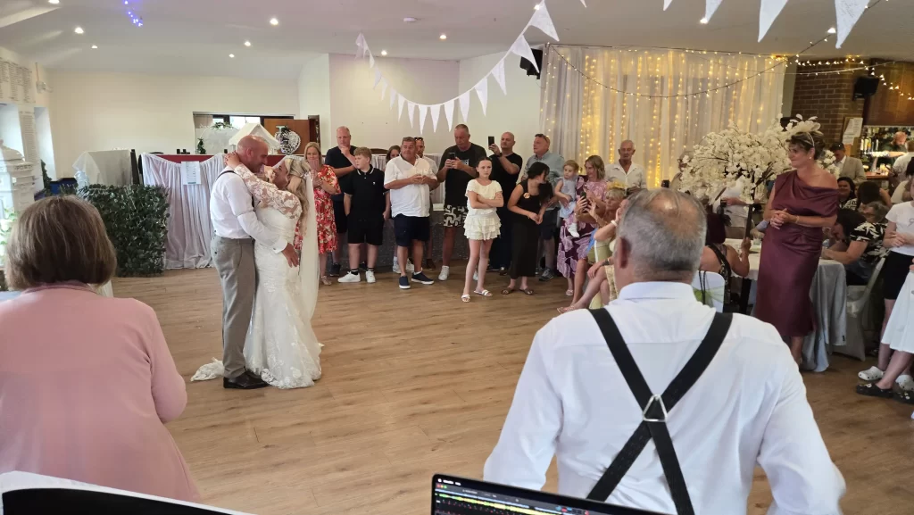 Bride and groom sharing their first dance surrounded by family and friends