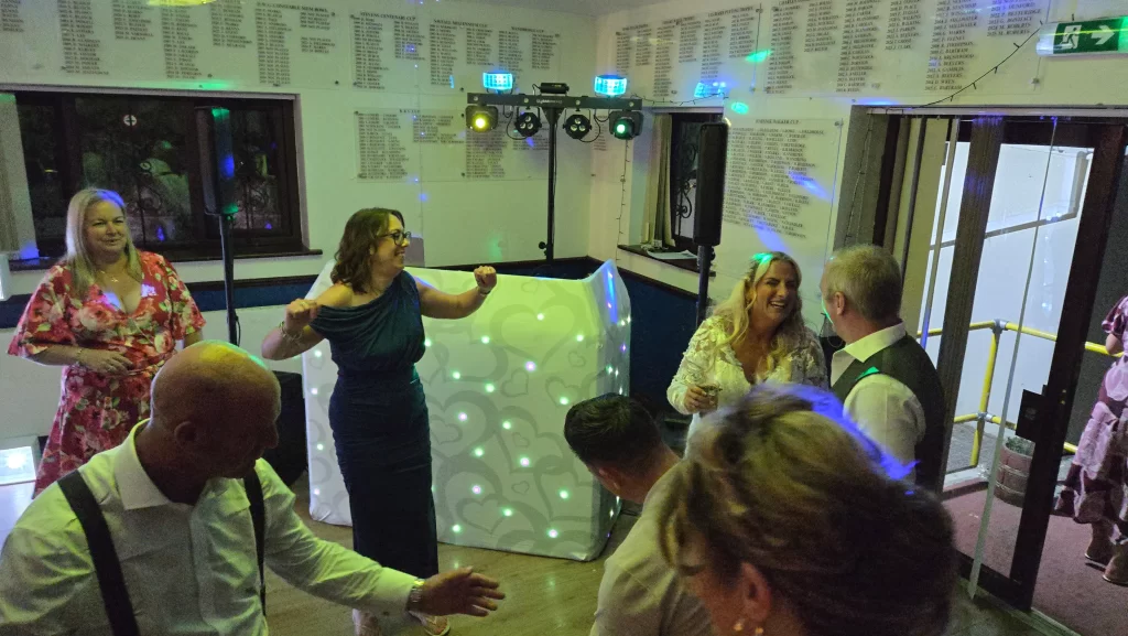 Wedding guests dancing and celebrating beside the wedding DJ setup