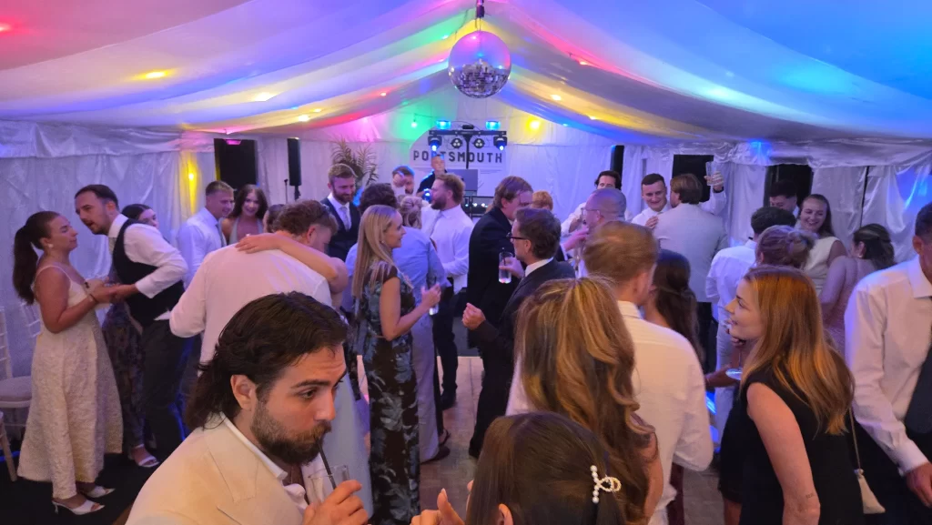 Wedding guests enjoying the dance floor under colourful lighting at Portsmouth Distillery