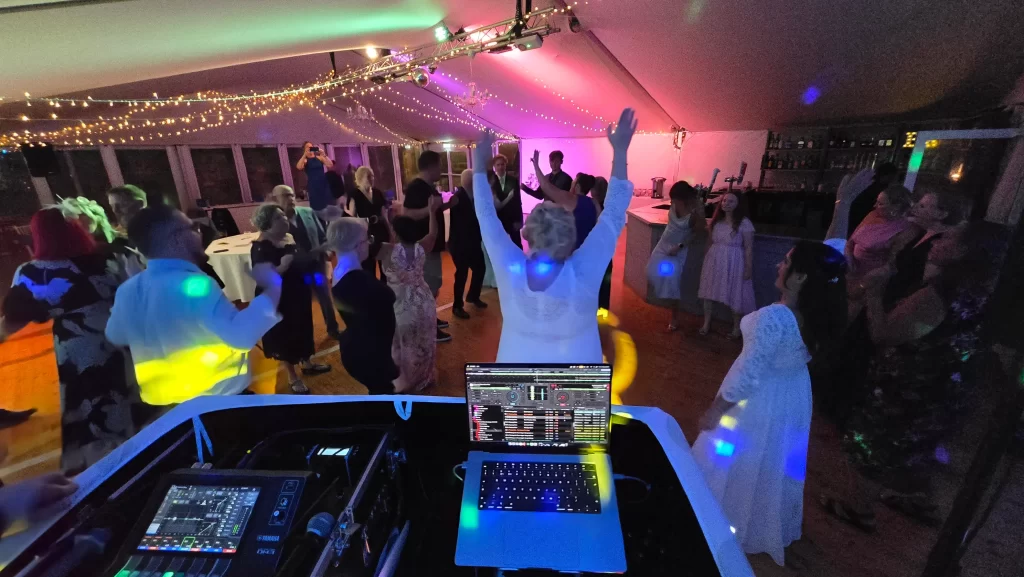 Bride and guests dancing beneath colourful DJ lighting at a Southsea Castle wedding