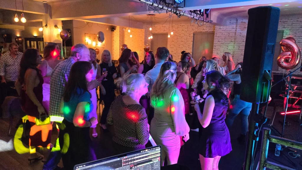 Guests dancing at a 21st birthday party at Portsmouth Rifle Club, with colourful DJ lighting by Heard The Beat.